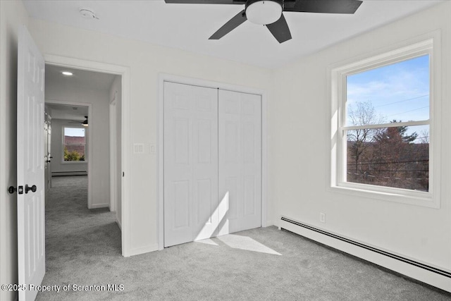 unfurnished bedroom featuring a closet, carpet floors, a ceiling fan, and a baseboard radiator