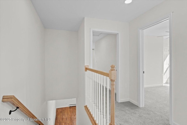 corridor with an upstairs landing, carpet, and baseboards