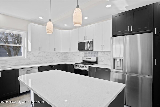 kitchen with dark cabinets, backsplash, light countertops, and appliances with stainless steel finishes