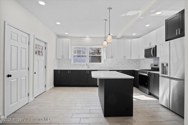 kitchen with a sink, backsplash, appliances with stainless steel finishes, a center island, and dark cabinets