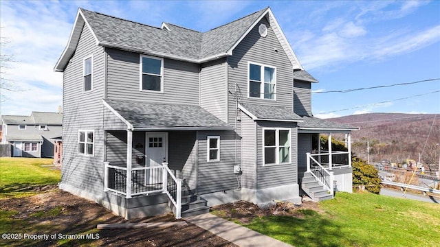 view of front facade with a porch, a front yard, and a shingled roof