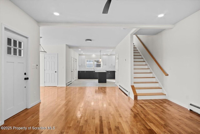 foyer with light wood-style flooring, stairway, a baseboard heating unit, and ceiling fan