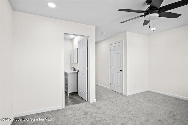 unfurnished bedroom featuring baseboards, a sink, and carpet