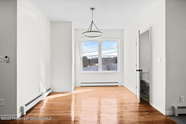 unfurnished dining area with wood finished floors and a baseboard heating unit