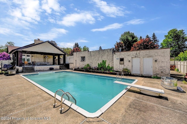 view of pool featuring a diving board and a patio