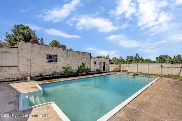 view of swimming pool featuring a patio and a diving board