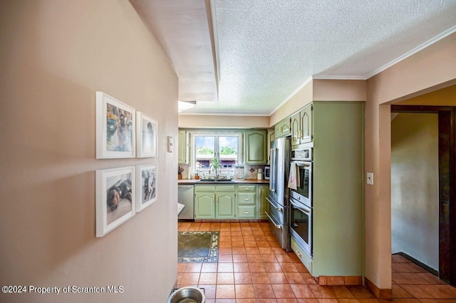 kitchen with appliances with stainless steel finishes, tasteful backsplash, sink, light tile patterned floors, and green cabinetry