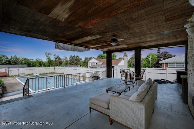 pool at dusk featuring ceiling fan and a patio area