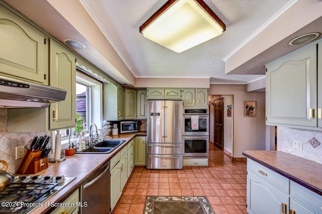 kitchen with sink, stainless steel appliances, green cabinets, decorative backsplash, and light tile patterned floors