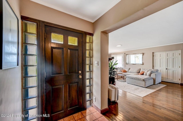 foyer entrance with light wood-type flooring and crown molding