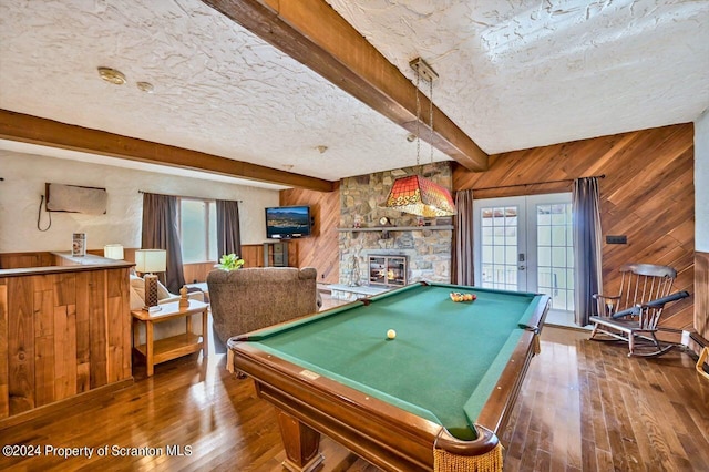 game room featuring beam ceiling, wood walls, french doors, and a textured ceiling