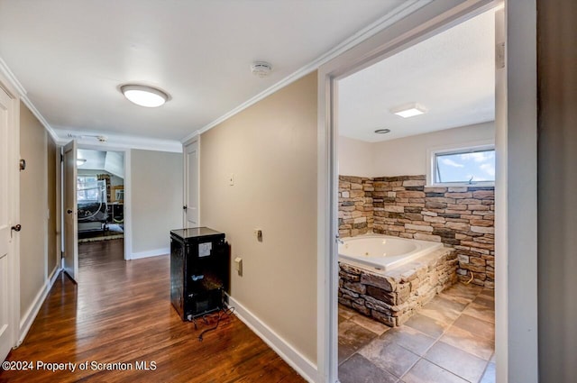 bathroom with a washtub, wood-type flooring, and ornamental molding