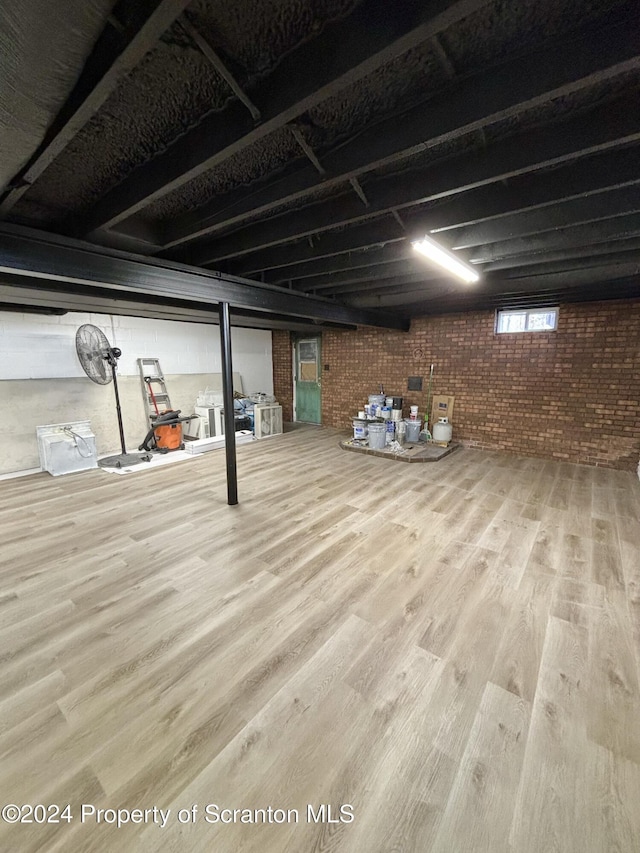 basement featuring hardwood / wood-style flooring and brick wall