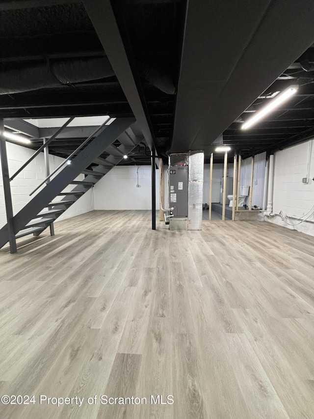 basement with hardwood / wood-style flooring and heating unit