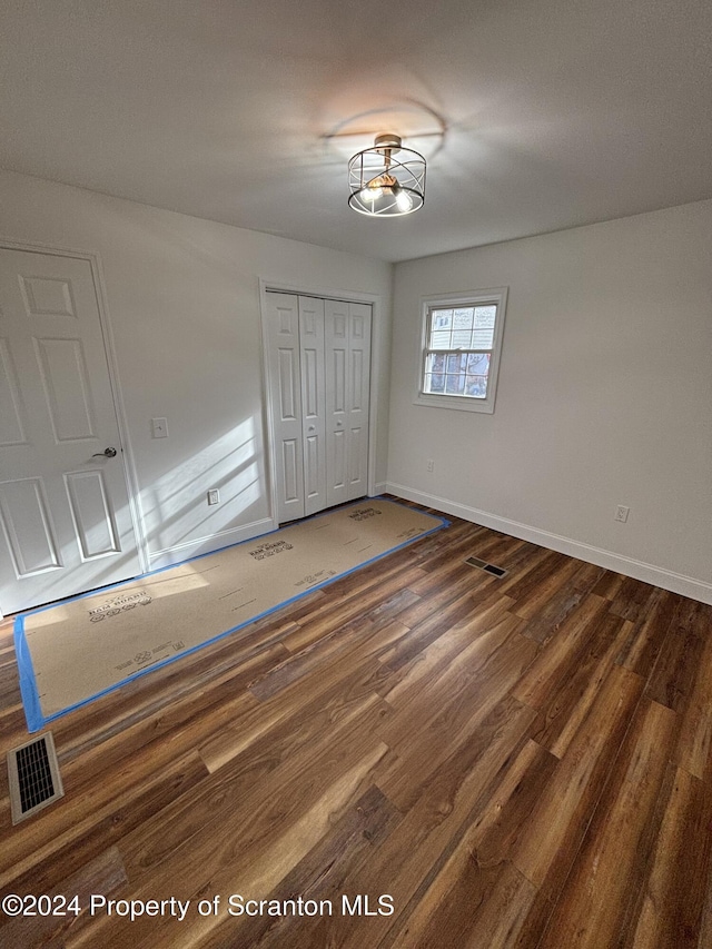 unfurnished bedroom with dark wood-type flooring and a closet