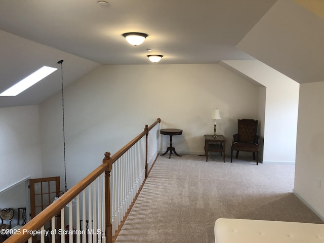 hallway with lofted ceiling with skylight and light carpet