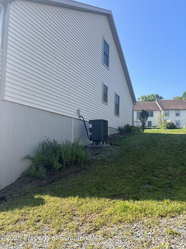 view of property exterior featuring central AC unit and a lawn