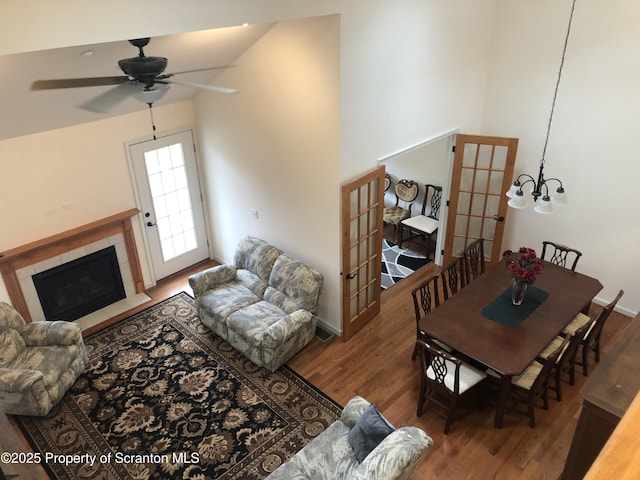 living room featuring a tile fireplace, wood-type flooring, ceiling fan with notable chandelier, and french doors