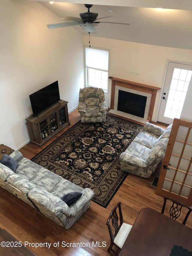 living room featuring a tile fireplace, hardwood / wood-style floors, and ceiling fan