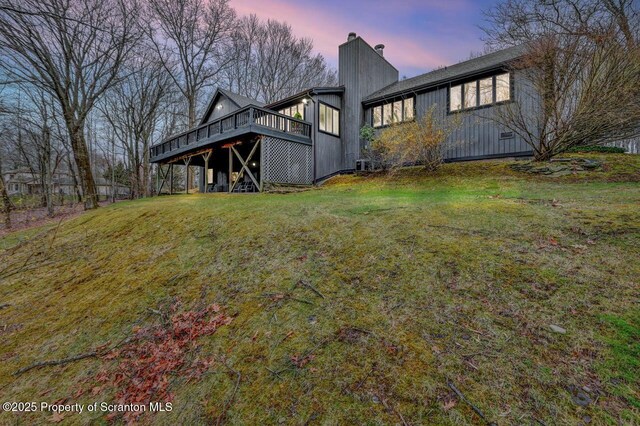 back of house with a wooden deck, a chimney, a yard, and central air condition unit