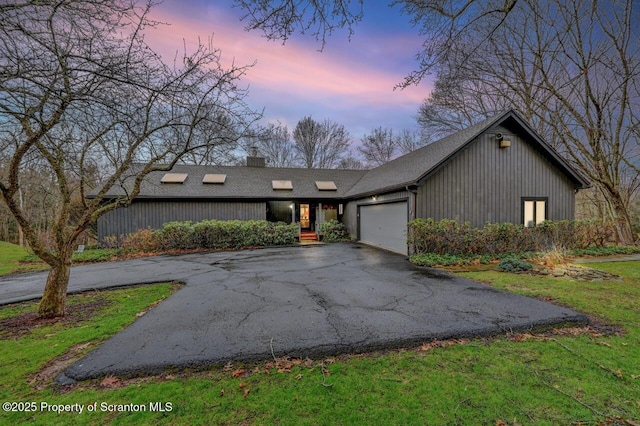 mid-century modern home with a chimney, aphalt driveway, and a garage