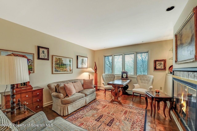 living area featuring wood finished floors, a tiled fireplace, and baseboards