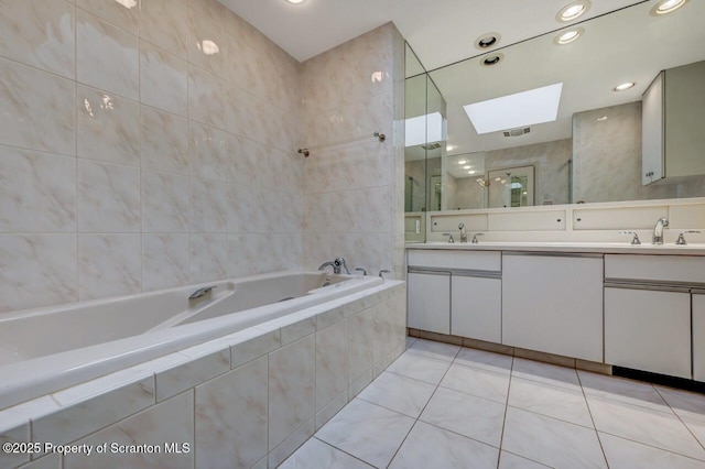 bathroom with a sink, double vanity, tiled shower, a skylight, and a garden tub