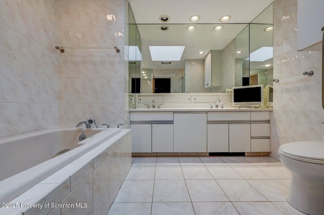 bathroom featuring a bath, tile patterned floors, a skylight, and tile walls