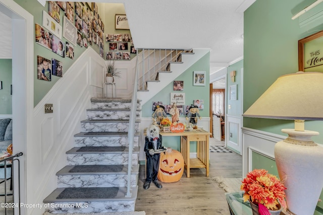 stairway with hardwood / wood-style flooring and ornamental molding