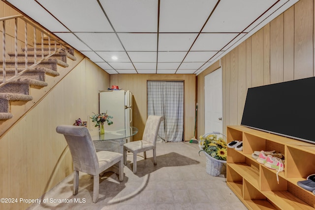 dining room featuring a drop ceiling and wooden walls