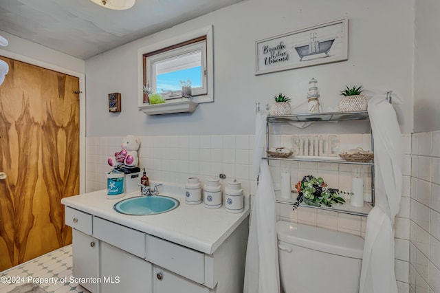 bathroom featuring tile patterned flooring, vanity, toilet, and tile walls