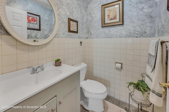 bathroom with vanity, toilet, and tile walls