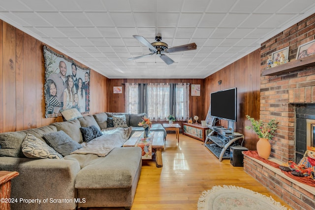 living room featuring ceiling fan, light hardwood / wood-style floors, and a brick fireplace