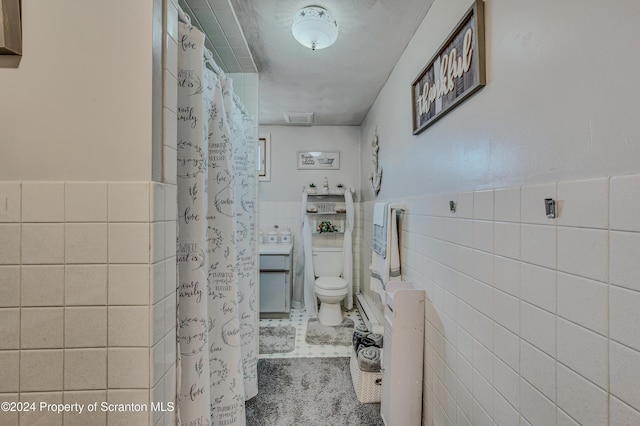 bathroom with tile patterned flooring, tile walls, and toilet