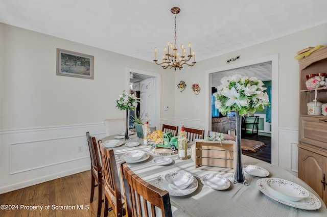 dining space with dark hardwood / wood-style floors and an inviting chandelier