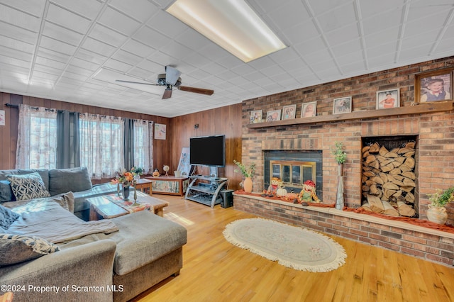 living room featuring ceiling fan, wood-type flooring, and a brick fireplace