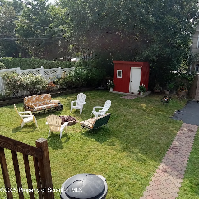 view of yard featuring a storage unit, an outdoor structure, an outdoor fire pit, and fence private yard