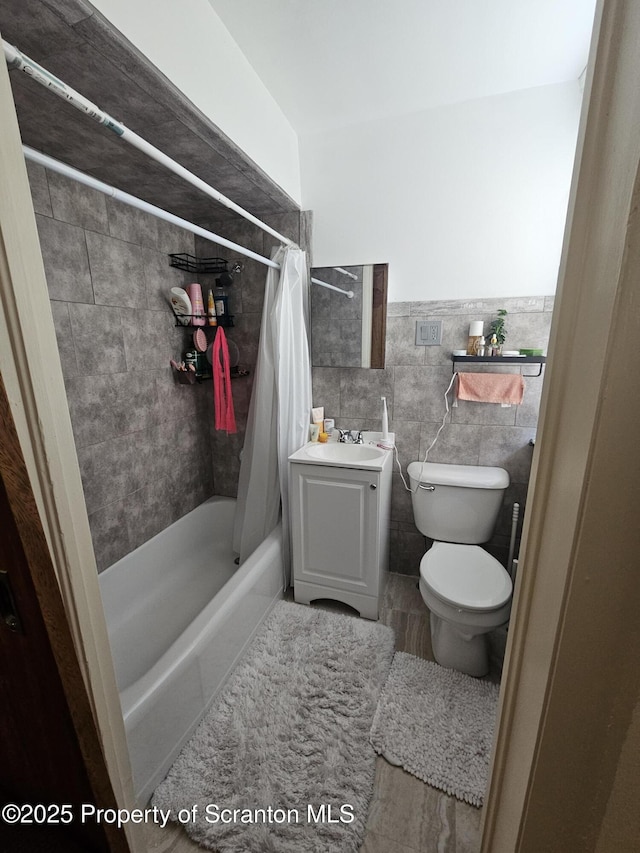 full bathroom featuring vanity, toilet, tile walls, and shower / tub combo