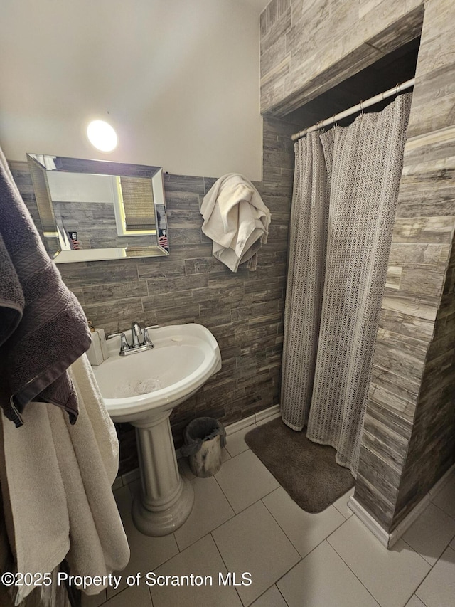 bathroom with a sink, tile walls, tile patterned floors, and curtained shower