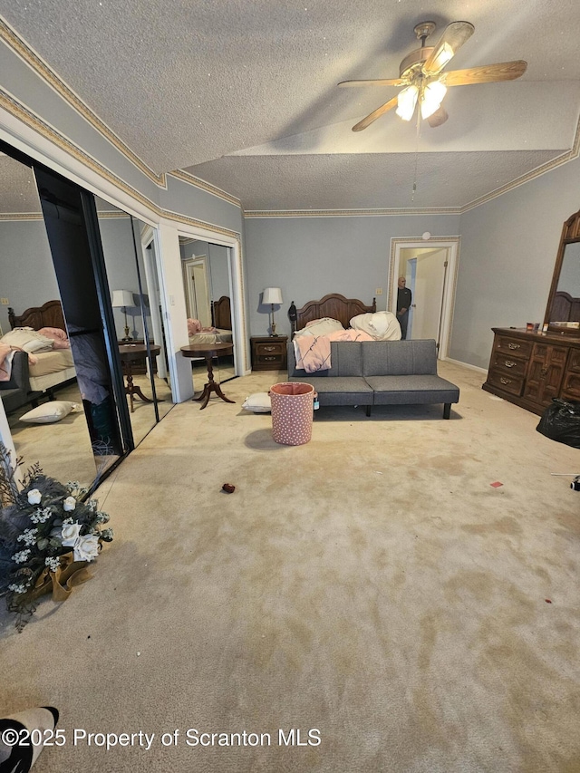 bedroom featuring carpet floors, ornamental molding, two closets, ceiling fan, and a textured ceiling