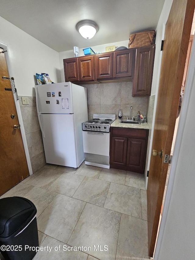 kitchen with freestanding refrigerator, range with electric cooktop, a sink, and tasteful backsplash