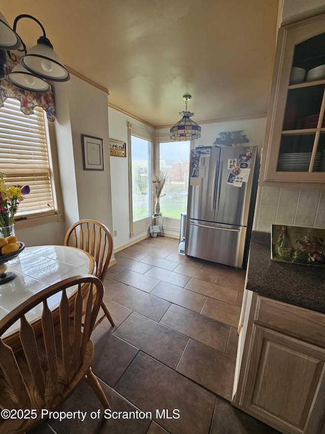 dining area with baseboards, ornamental molding, and dark tile patterned floors