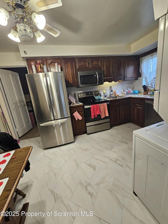 kitchen with a ceiling fan, marble finish floor, washer / clothes dryer, a sink, and appliances with stainless steel finishes