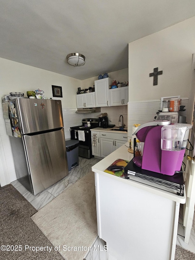 kitchen featuring a sink, marble finish floor, freestanding refrigerator, white cabinetry, and black range with electric cooktop