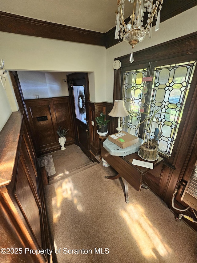 foyer entrance with ornamental molding, wainscoting, and a notable chandelier
