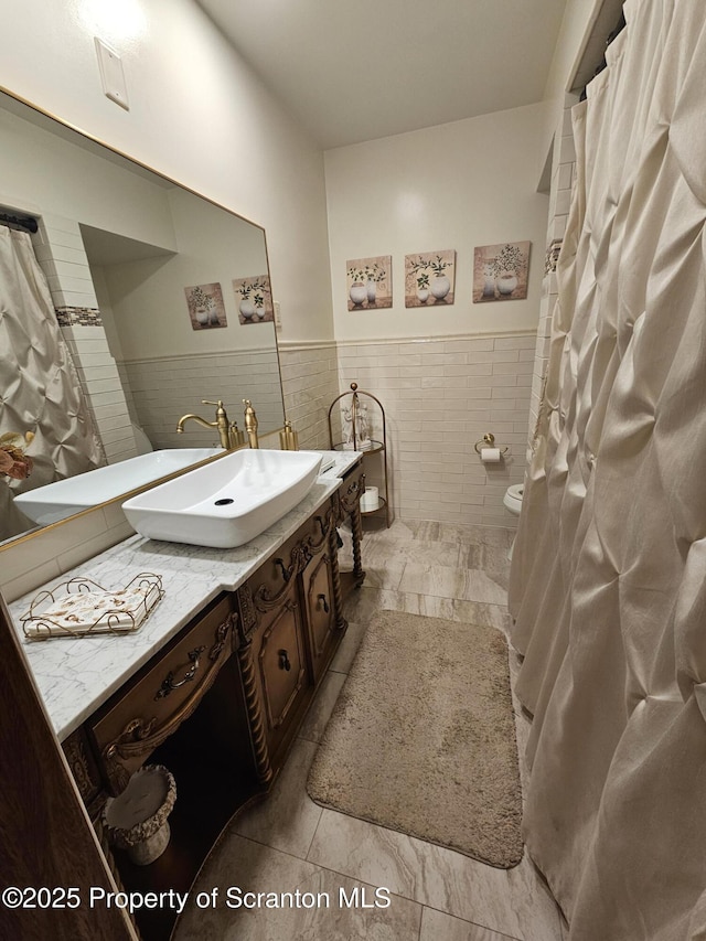 bathroom featuring tile walls, tile patterned flooring, a wainscoted wall, vanity, and toilet