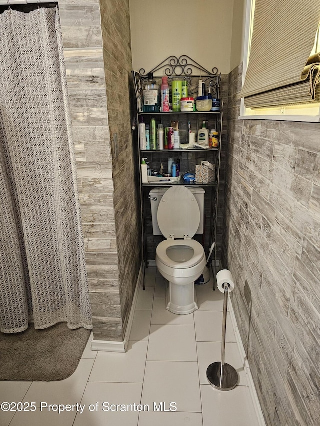 bathroom featuring tile walls, tile patterned flooring, and toilet