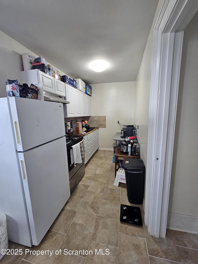 kitchen featuring white cabinets, black electric range, freestanding refrigerator, baseboards, and under cabinet range hood