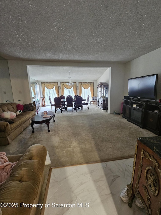 carpeted living room featuring a chandelier, a textured ceiling, and marble finish floor
