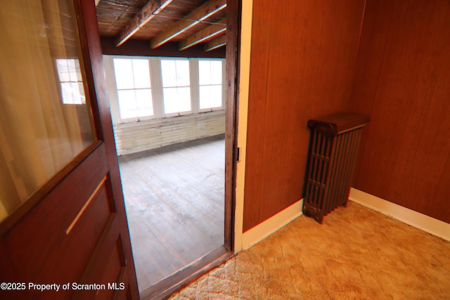 hall with beamed ceiling and brick wall